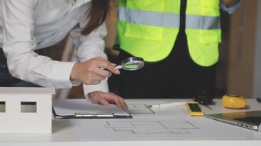 Mimari planlı ev projesi üzerinde çalışan mimar, arka planda mimari konsept