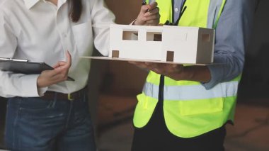 Ev modeliyle çalışan mühendis ya da kadın mimar.