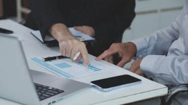 İş adamları modern bir ofiste dizüstü bilgisayarı tartışıyor ve üzerinde çalışıyor.