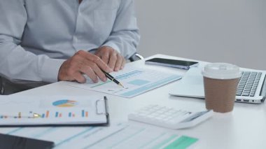 İş adamı masadaki iş verilerini hesaplamak için hesap makinesi kullanıyor. finansal kavram