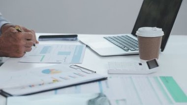 İşadamı elinde belge olan bir bilgisayar üzerinde çalışıyor..