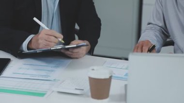 Genç adam ve iş kadını ofiste oturuyor ve proje üzerinde çalışıyorlar..