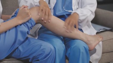 Genç doktor muayenehanede hastanın ayağını muayene ediyor.