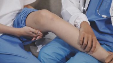 Üniformalı kadın doktor hastane ofisinde dizini inceliyor.