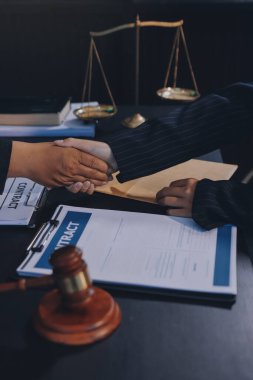 Hukuki bir duruşma sırasında ön planda adalet ve tokmak ile anlaşmaya varan iki avukat el sıkışıyor.