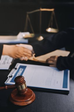 Hukuki bir duruşma sırasında ön planda adalet ve tokmak ile anlaşmaya varan iki avukat el sıkışıyor.