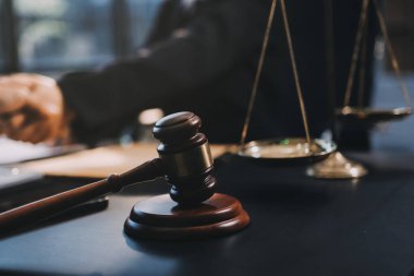 Hukuki bir duruşma sırasında ön planda adalet ve tokmak ile anlaşmaya varan iki avukat el sıkışıyor.