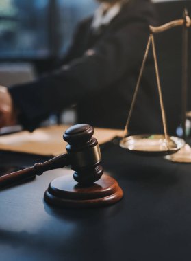 Hukuki bir duruşma sırasında ön planda adalet ve tokmak ile anlaşmaya varan iki avukat el sıkışıyor.