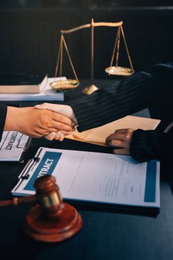 Hukuki bir duruşma sırasında ön planda adalet ve tokmak ile anlaşmaya varan iki avukat el sıkışıyor.