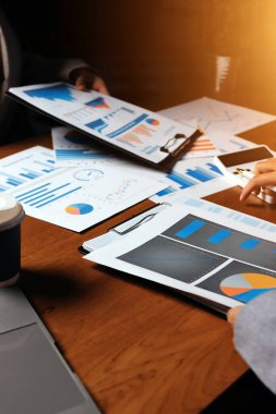 Group of confident business people point to graphs and charts to analyze market data, balance sheet, account, net profit to plan new sales strategies to increase production capacity.