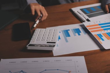 Group of confident business people point to graphs and charts to analyze market data, balance sheet, account, net profit to plan new sales strategies to increase production capacity.