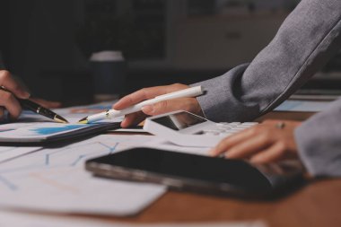 Group of confident business people point to graphs and charts to analyze market data, balance sheet, account, net profit to plan new sales strategies to increase production capacity.