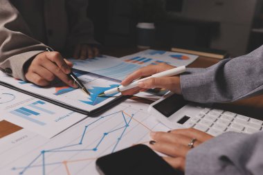 Group of confident business people point to graphs and charts to analyze market data, balance sheet, account, net profit to plan new sales strategies to increase production capacity.