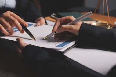 Ofisteki çekici genç avukat iş kadını ve avukatlar ofisdeki ahşap masada pirinç pullu kağıtları tartışıyorlar. Hukuk, hukuk hizmetleri, danışmanlık, Adalet ve emlak kavramı.