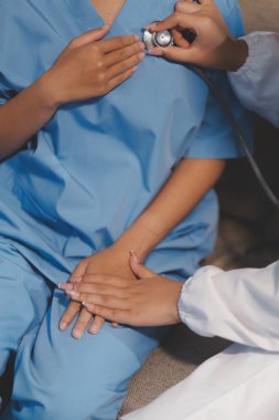 Yaşlı bir kadının kalp atışlarını dinleyen bir doktorun yakın çekimi.