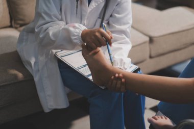 Kadın bir doktor, eklem iltihabı nedeniyle diz ağrısı olan yaşlı bir hastayı muayene eder. Hastaya iyileşme sürecinde yardım ediliyor, ağrı yönetimi ve hareket kabiliyetinin iyileştirilmesi üzerinde duruluyor..