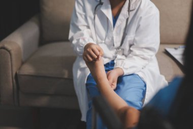 Kadın bir doktor, eklem iltihabı nedeniyle diz ağrısı olan yaşlı bir hastayı muayene eder. Hastaya iyileşme sürecinde yardım ediliyor, ağrı yönetimi ve hareket kabiliyetinin iyileştirilmesi üzerinde duruluyor..