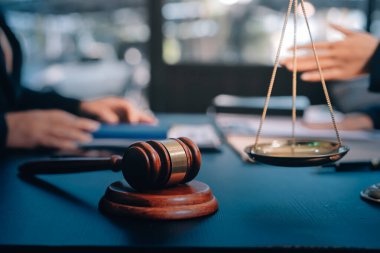 Hukuki bir duruşma sırasında ön planda adalet ve tokmak ile anlaşmaya varan iki avukat el sıkışıyor.