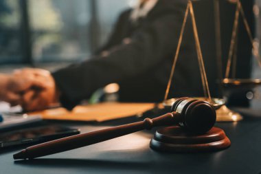 Hukuki bir duruşma sırasında ön planda adalet ve tokmak ile anlaşmaya varan iki avukat el sıkışıyor.