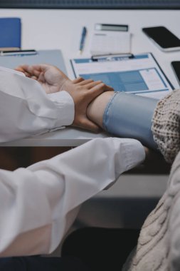 Steteskopla sfenometre kullanan bir doktor hastanede kan basıncını ölçüyor..
