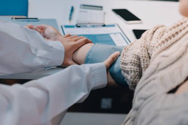 Steteskopla sfenometre kullanan bir doktor hastanede kan basıncını ölçüyor..