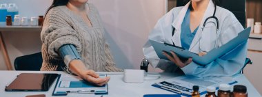 Steteskopla sfenometre kullanan bir doktor hastanede kan basıncını ölçüyor..