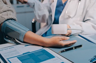 Steteskopla sfenometre kullanan bir doktor hastanede kan basıncını ölçüyor..