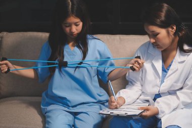 Erkek bir hasta üzerinde egzersiz band klinikte rehabilitasyon fizyoterapi kavramı ile onun kol germe egzersiz tedavisi verirken yardımcı doktor fizyoterapist