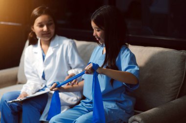 Erkek bir hasta üzerinde egzersiz band klinikte rehabilitasyon fizyoterapi kavramı ile onun kol germe egzersiz tedavisi verirken yardımcı doktor fizyoterapist