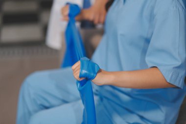 Erkek bir hasta üzerinde egzersiz band klinikte rehabilitasyon fizyoterapi kavramı ile onun kol germe egzersiz tedavisi verirken yardımcı doktor fizyoterapist