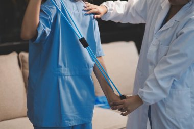 Erkek bir hasta üzerinde egzersiz band klinikte rehabilitasyon fizyoterapi kavramı ile onun kol germe egzersiz tedavisi verirken yardımcı doktor fizyoterapist