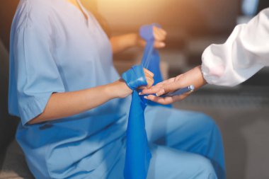 Erkek bir hasta üzerinde egzersiz band klinikte rehabilitasyon fizyoterapi kavramı ile onun kol germe egzersiz tedavisi verirken yardımcı doktor fizyoterapist