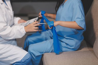 Erkek bir hasta üzerinde egzersiz band klinikte rehabilitasyon fizyoterapi kavramı ile onun kol germe egzersiz tedavisi verirken yardımcı doktor fizyoterapist