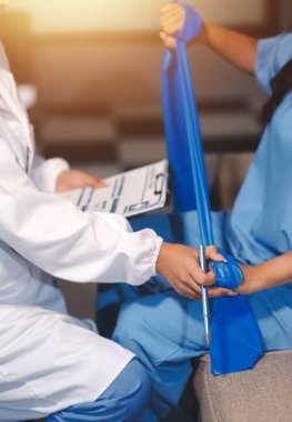 Erkek bir hasta üzerinde egzersiz band klinikte rehabilitasyon fizyoterapi kavramı ile onun kol germe egzersiz tedavisi verirken yardımcı doktor fizyoterapist