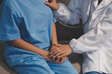 Yaşlı bir kadının kalp atışlarını dinleyen bir doktorun yakın çekimi.