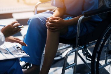 Kadın bir doktor, eklem iltihabı nedeniyle diz ağrısı olan yaşlı bir hastayı muayene eder. Hastaya iyileşme sürecinde yardım ediliyor, ağrı yönetimi ve hareket kabiliyetinin iyileştirilmesi üzerinde duruluyor..