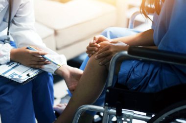 Kadın bir doktor, eklem iltihabı nedeniyle diz ağrısı olan yaşlı bir hastayı muayene eder. Hastaya iyileşme sürecinde yardım ediliyor, ağrı yönetimi ve hareket kabiliyetinin iyileştirilmesi üzerinde duruluyor..