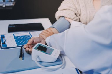 Steteskopla sfenometre kullanan bir doktor hastanede kan basıncını ölçüyor..