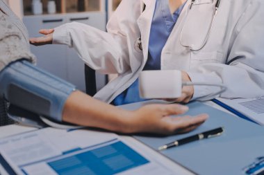 Steteskopla sfenometre kullanan bir doktor hastanede kan basıncını ölçüyor..