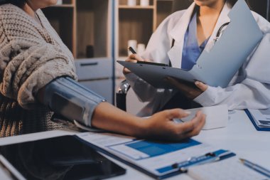 Steteskopla sfenometre kullanan bir doktor hastanede kan basıncını ölçüyor..