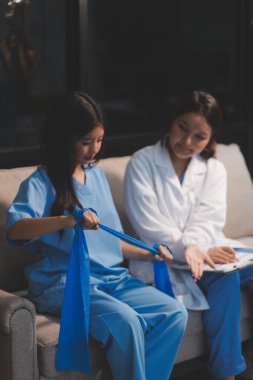 Erkek bir hasta üzerinde egzersiz band klinikte rehabilitasyon fizyoterapi kavramı ile onun kol germe egzersiz tedavisi verirken yardımcı doktor fizyoterapist