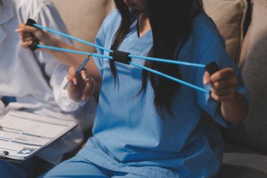 Erkek bir hasta üzerinde egzersiz band klinikte rehabilitasyon fizyoterapi kavramı ile onun kol germe egzersiz tedavisi verirken yardımcı doktor fizyoterapist