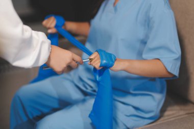 Erkek bir hasta üzerinde egzersiz band klinikte rehabilitasyon fizyoterapi kavramı ile onun kol germe egzersiz tedavisi verirken yardımcı doktor fizyoterapist