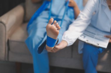 Kendine güvenen fizyoterapist, hastanın bacağını klinik odasında gerdirerek direnç bandı kullanmasına yardım ediyor..