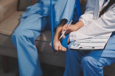 Kendine güvenen fizyoterapist, hastanın bacağını klinik odasında gerdirerek direnç bandı kullanmasına yardım ediyor..