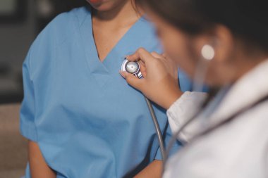 Yaşlı bir kadının kalp atışlarını dinleyen bir doktorun yakın çekimi.