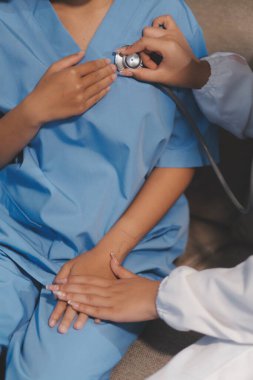 Yaşlı bir kadının kalp atışlarını dinleyen bir doktorun yakın çekimi.