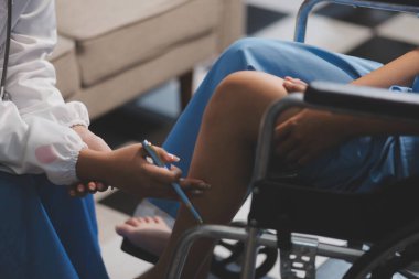 Kadın bir doktor, eklem iltihabı nedeniyle diz ağrısı olan yaşlı bir hastayı muayene eder. Hastaya iyileşme sürecinde yardım ediliyor, ağrı yönetimi ve hareket kabiliyetinin iyileştirilmesi üzerinde duruluyor..