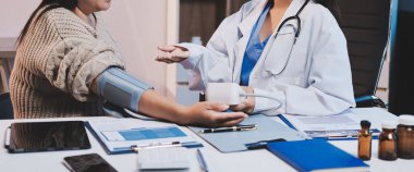 Steteskopla sfenometre kullanan bir doktor hastanede kan basıncını ölçüyor..