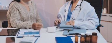 Steteskopla sfenometre kullanan bir doktor hastanede kan basıncını ölçüyor..